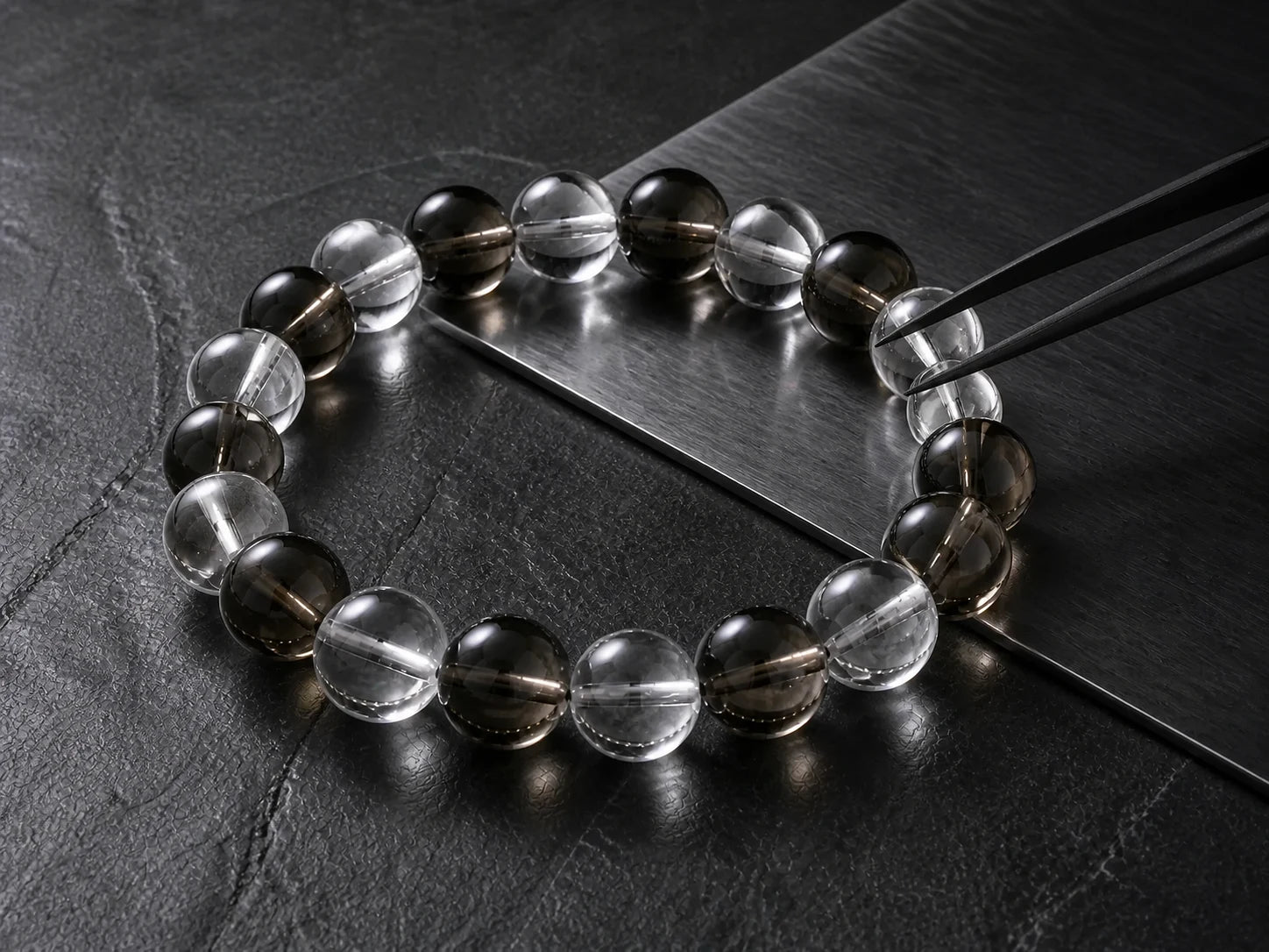 A complete clear and smoky quartz bracelet being aligned with precision black tweezers