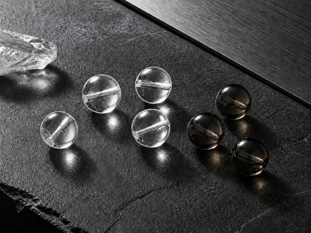 Full-size clear and smoky quartz beads on graphite