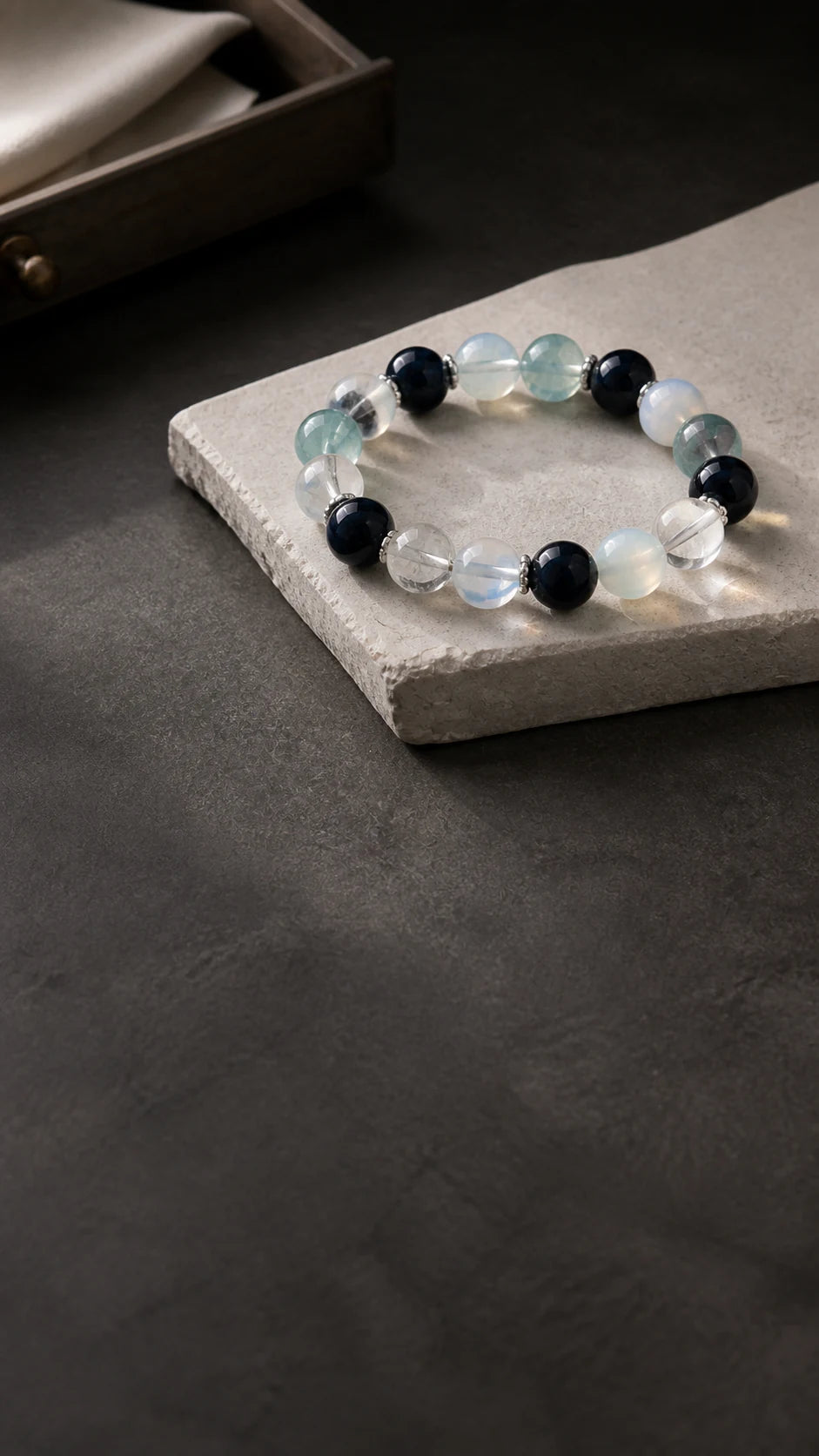 Aucelia crystal materials and bracelet on a dark editorial worktable